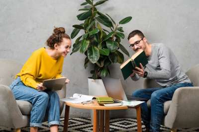 woman and man sitting in front of each other with books