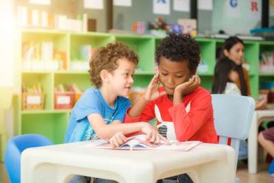 two boys reading a book at the desk two boys reading