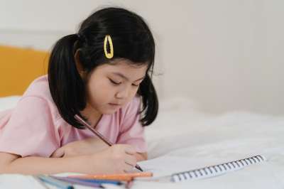 asian girl doing homework on the bed girl lying on the bed