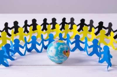 paper people holding hands around the globe global communication