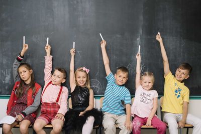 children posing by the blackboard
