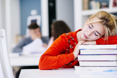 girl sleeping on a bunch of books