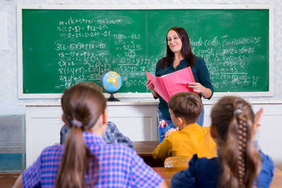 teacher with book in front of the class