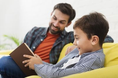 child reading a book with his father