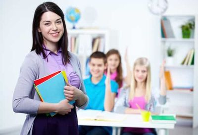 teacher with a pile of books and students on the background