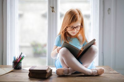 girl sitting on the window reading