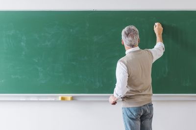 male teacher writing on blackboard