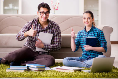 man and woman sitting on the floor in front of the laptop