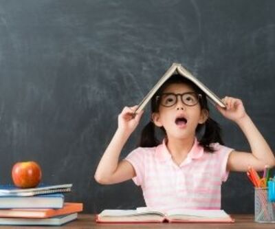 little girl covers her head with a book