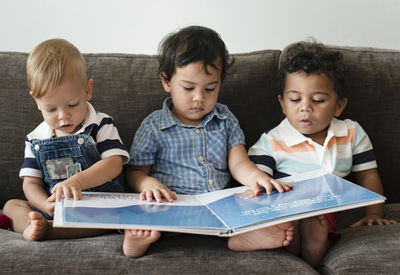 three little boys reading a book