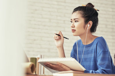 a chinese woman wearing headphones with a planner in her hands