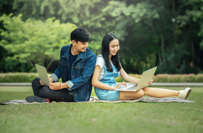 two asian students sitting on the green grass