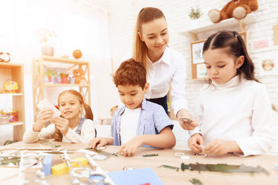 teacher helps students do crafts